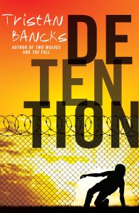 Book Cover from Tristan Bancks book Detention has barbed wired fences and the words detention in jumbled letters backed by a sunset